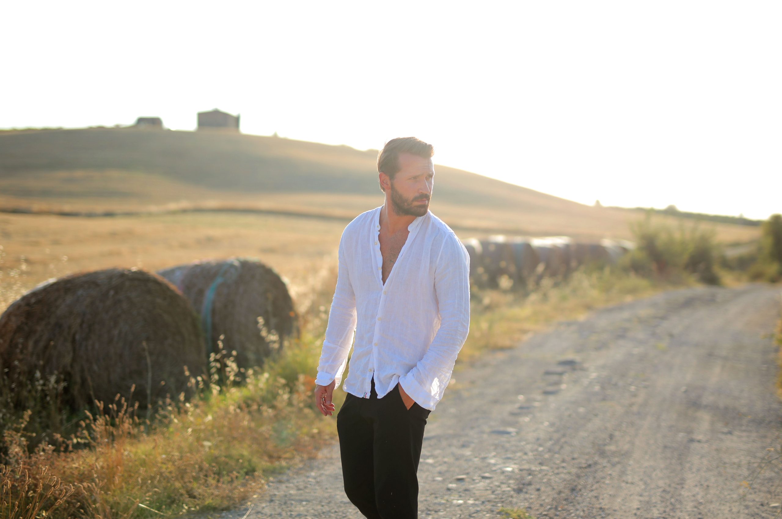 Homme en chemise blanche marchant le long d'un chemin rural
