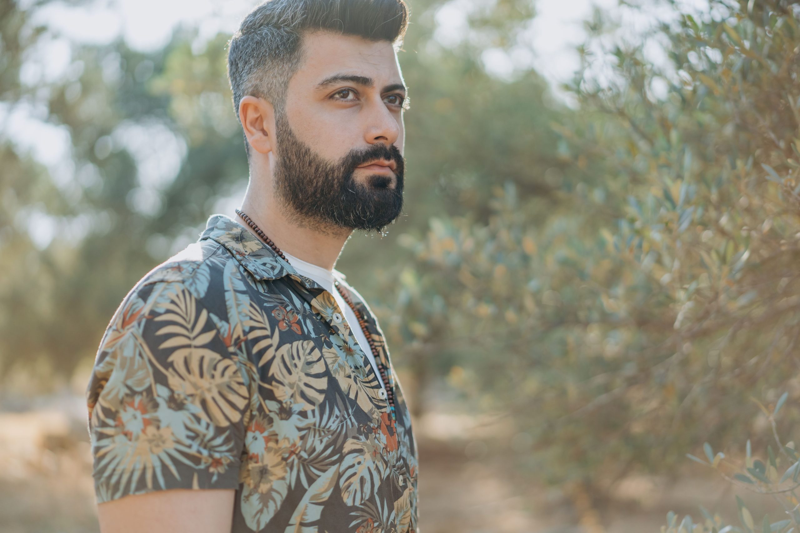 Homme barbu en chemise fleurie entouré de nature