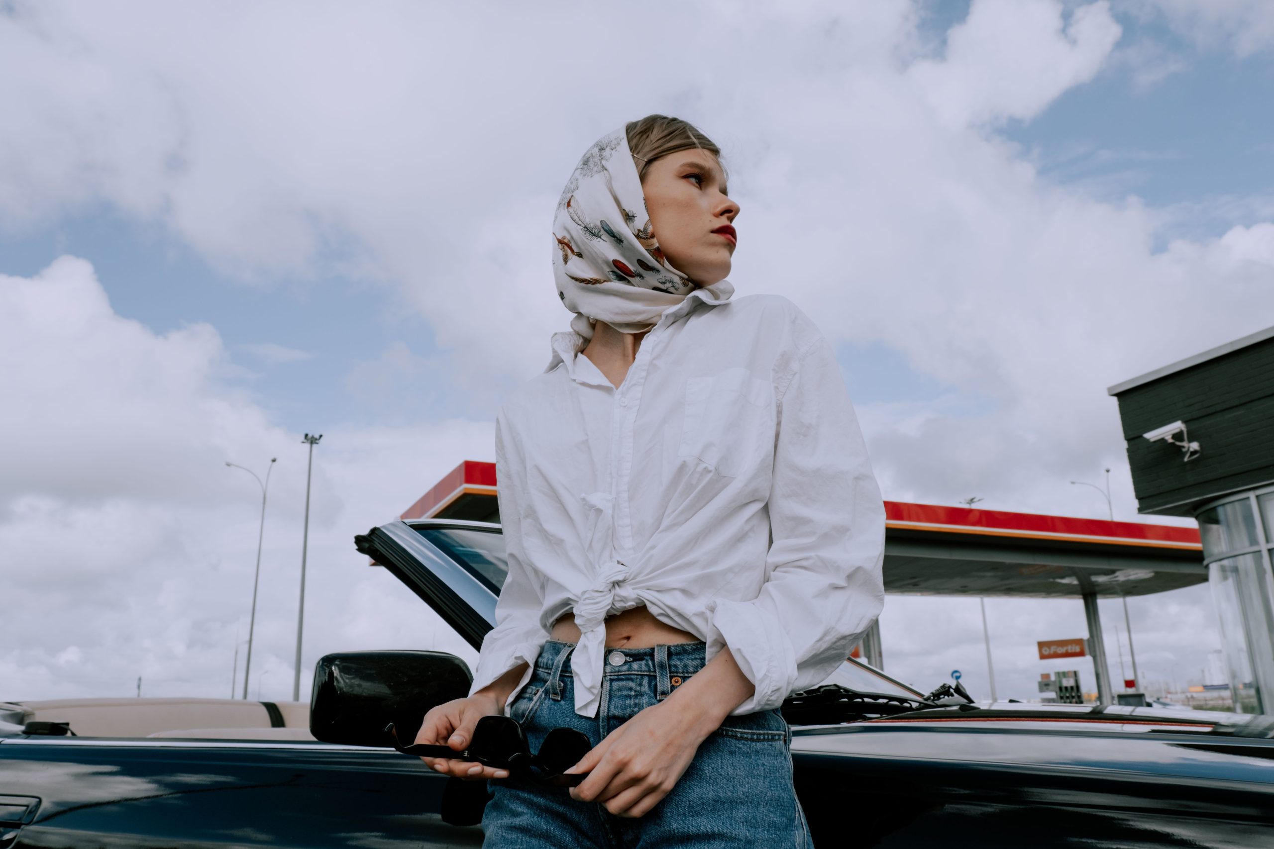 Femme stylisee en blouse blanche et foulard pres voiture