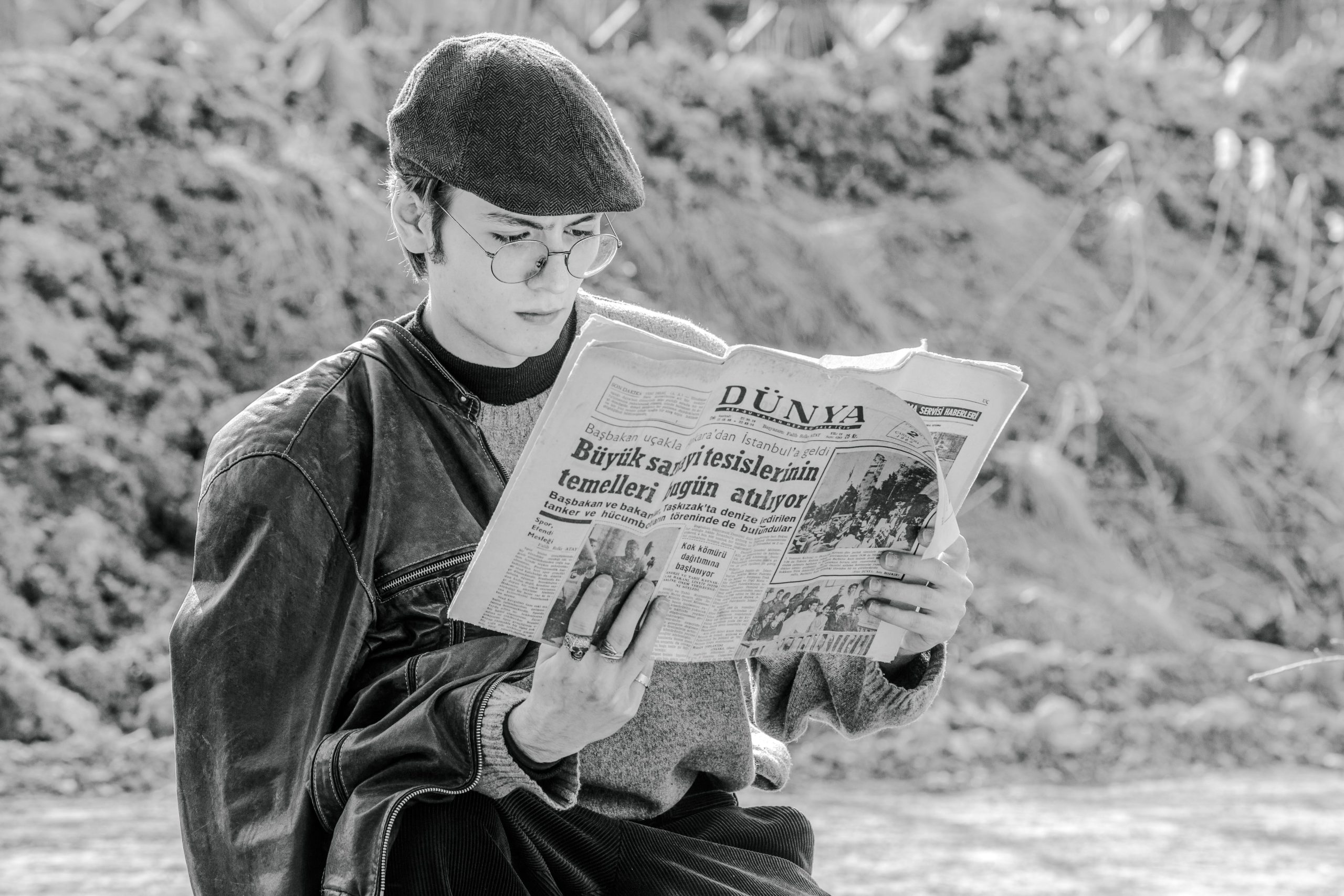 Homme élégant en casquette lisant journal dehors