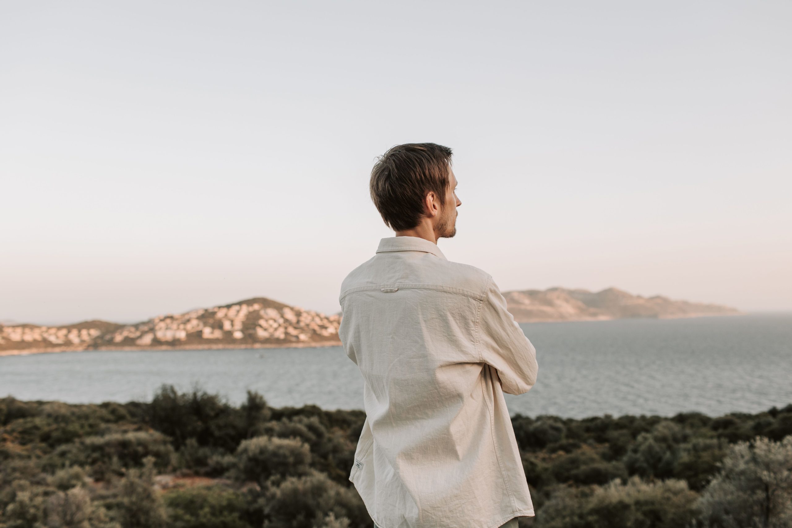 Homme contemplant la mer et les montagnes au coucher de soleil