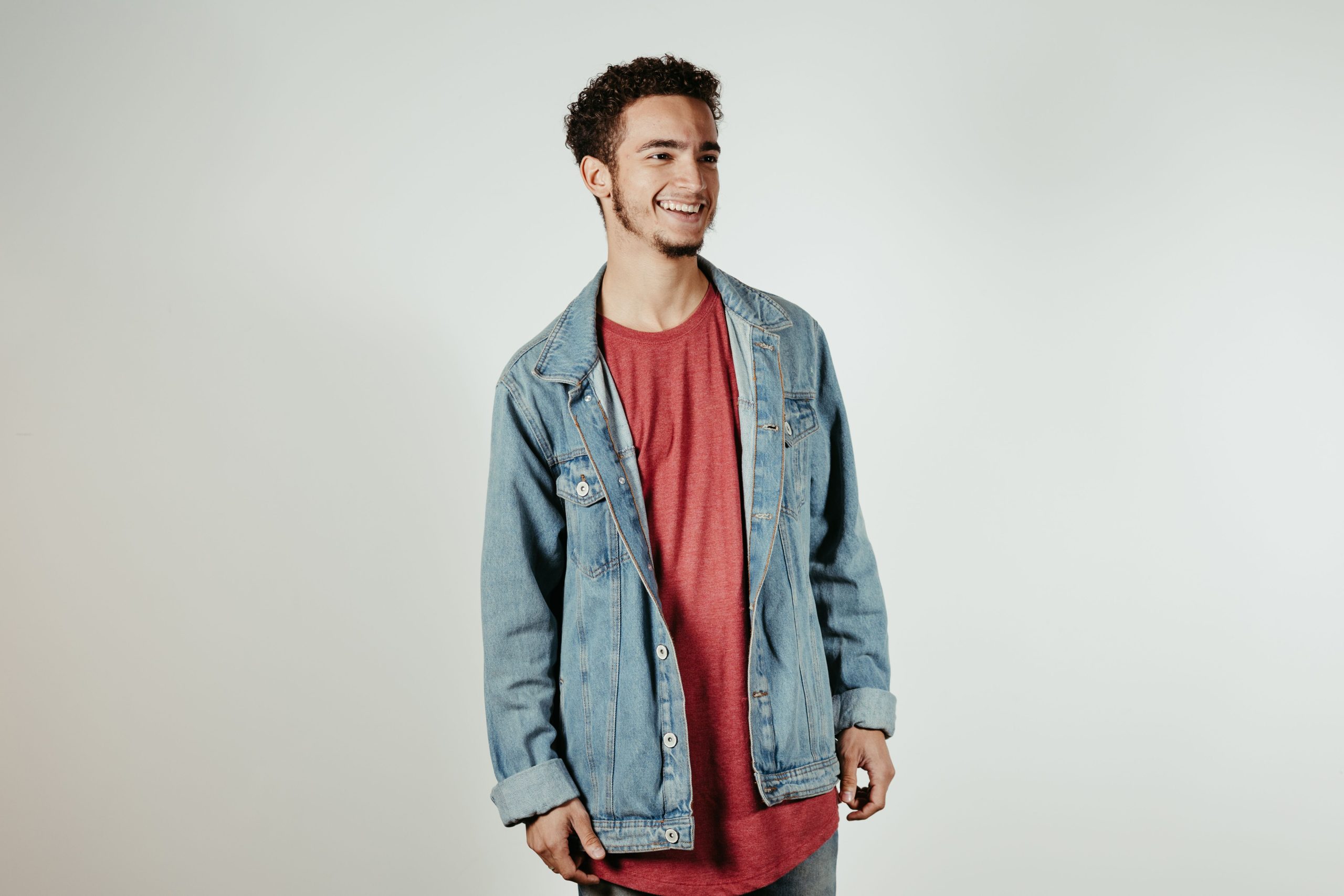Jeune homme souriant veste denim rose studio