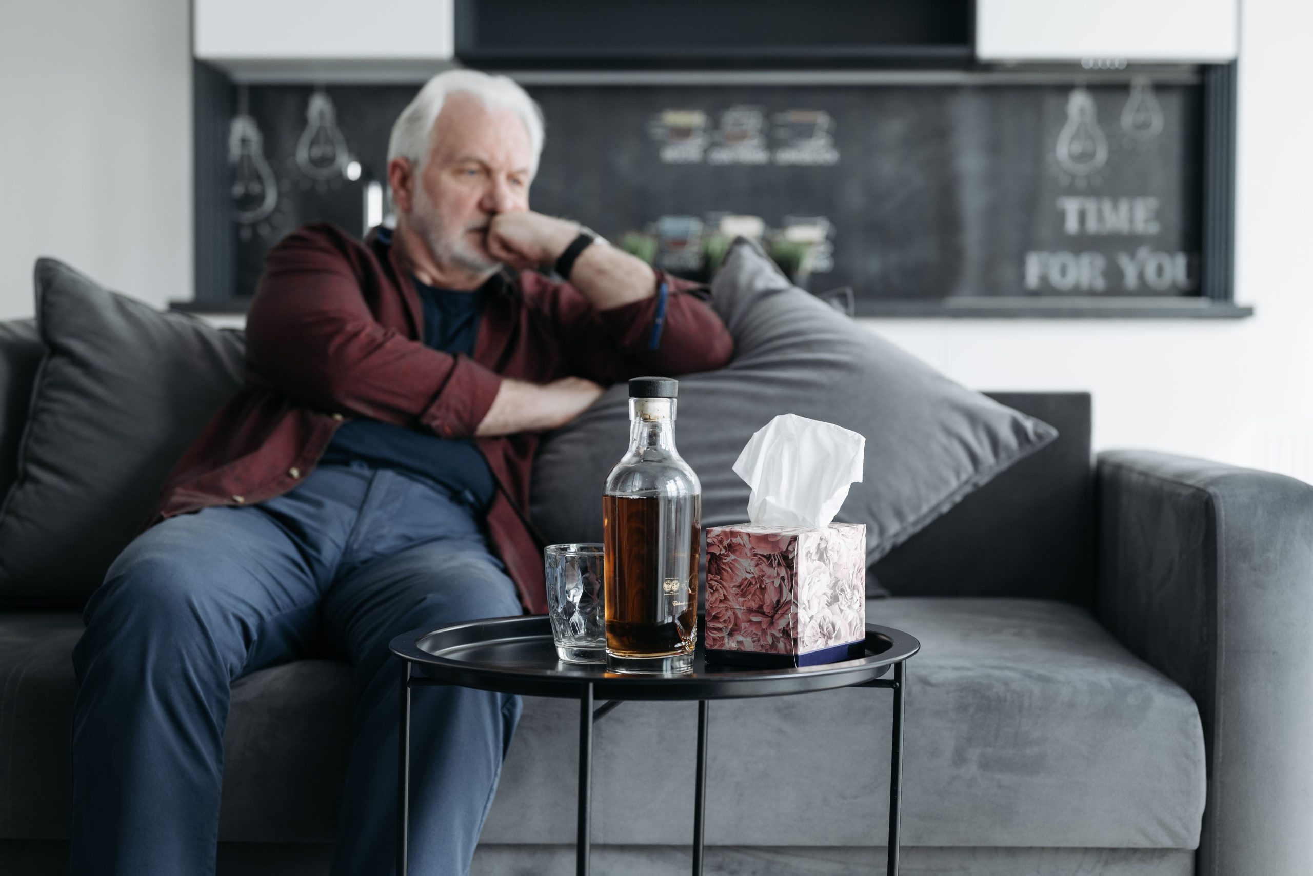 Homme senior pensif avec bouteille whiskey