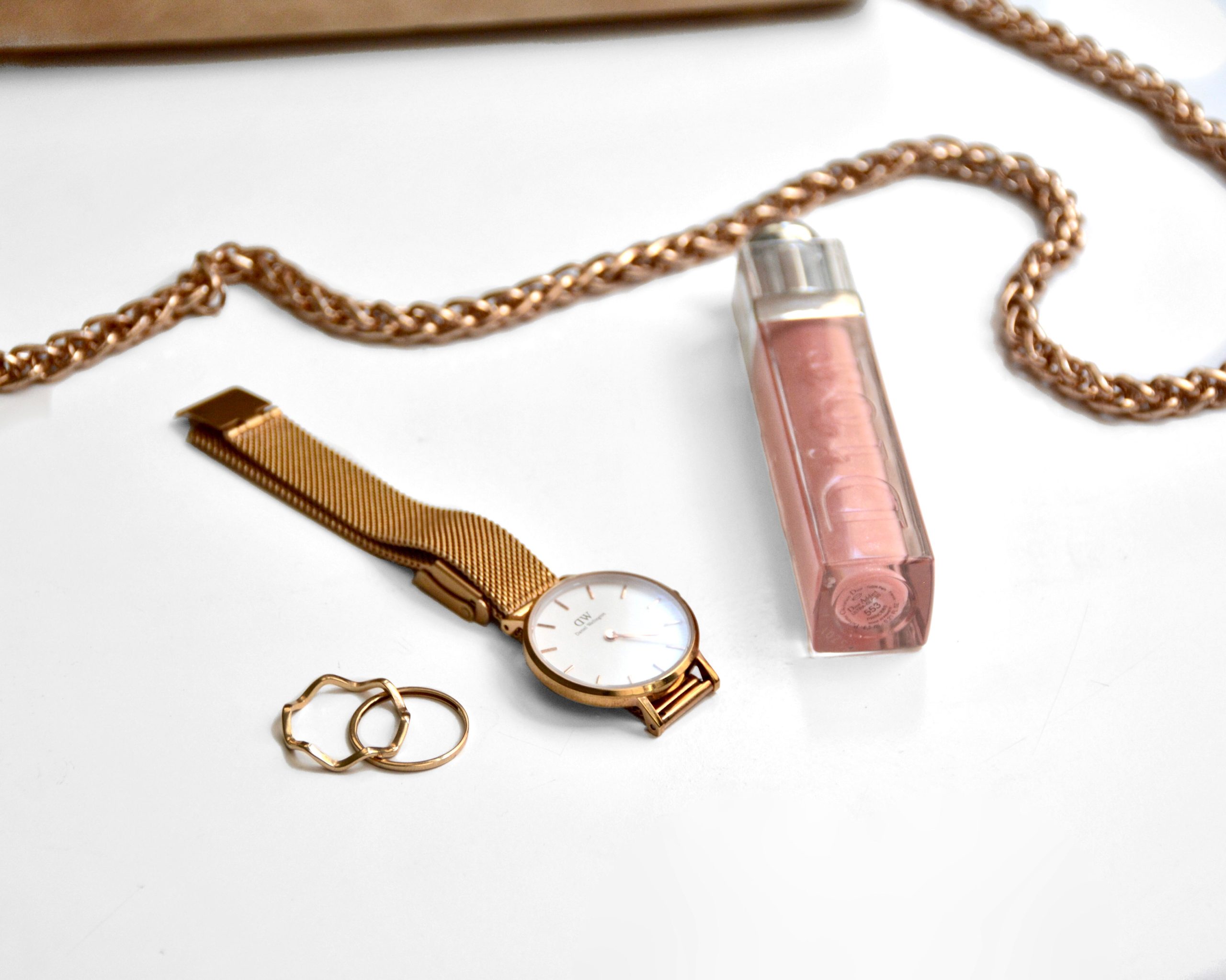 Montre dorée, bagues et accessoires sur fond blanc