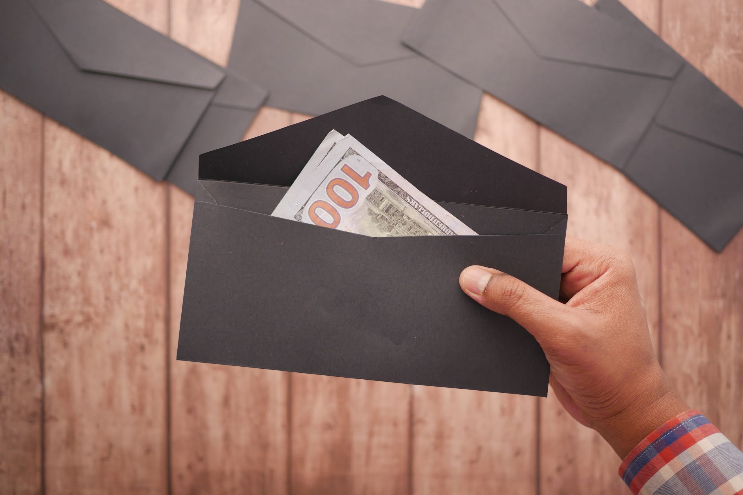 Main tenant enveloppe noire avec billet cent dollars