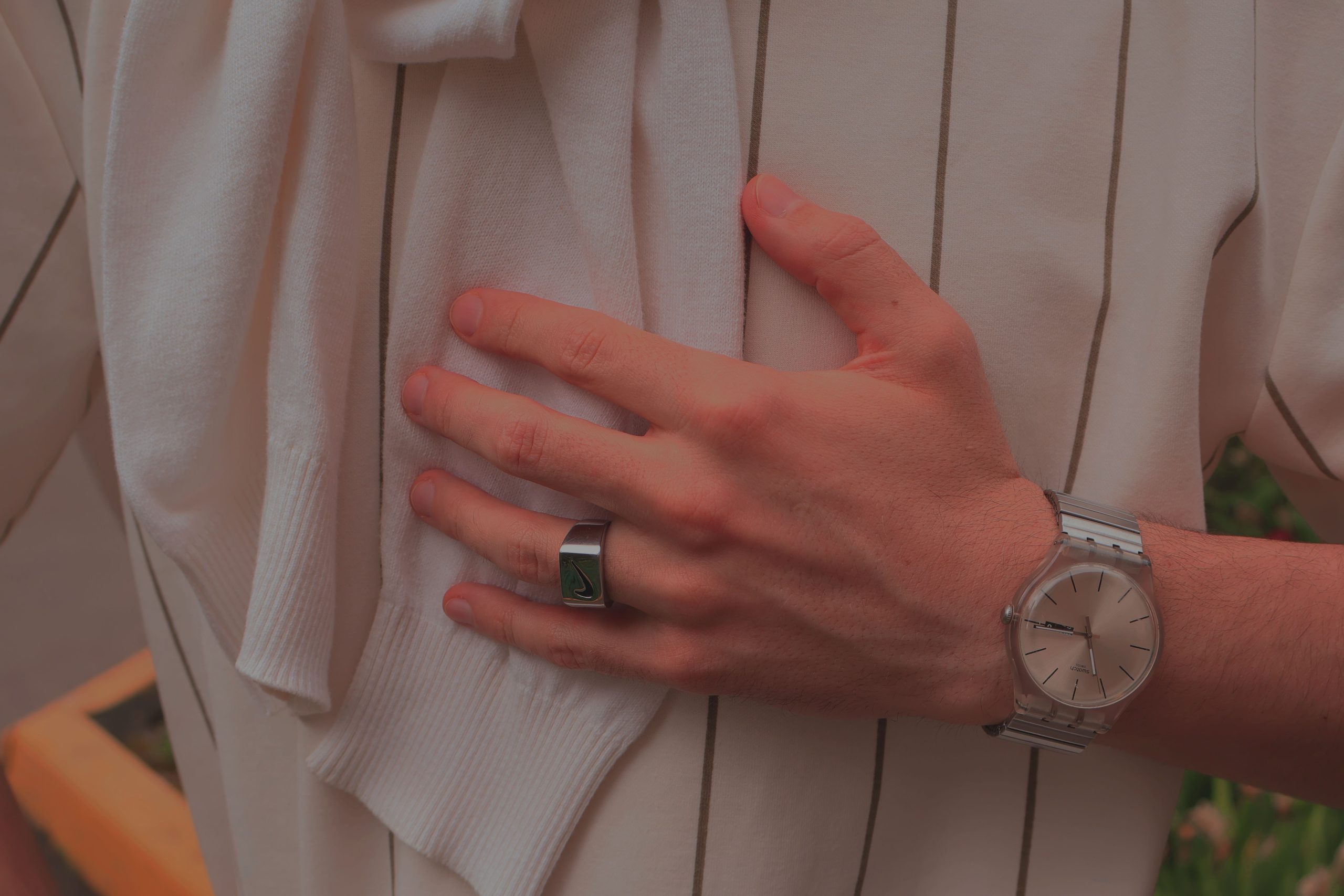 Main avec montre et bague tenant vêtement blanc