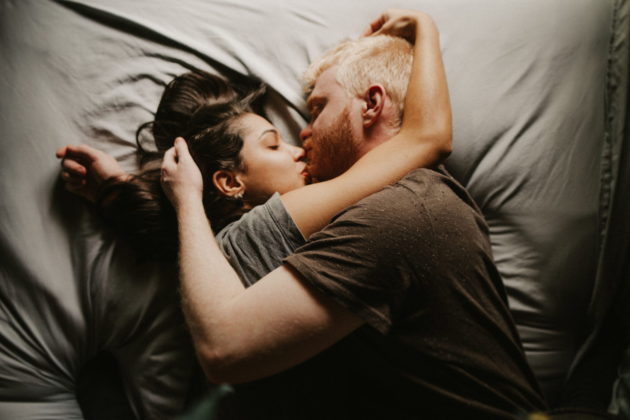 Jeune couple partageant un baiser romantique au lit